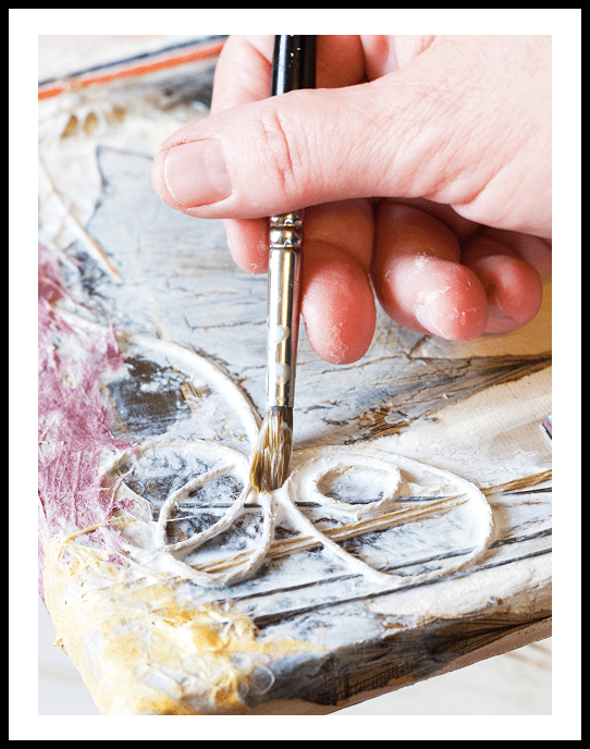 Hand painting textured artwork with brush.