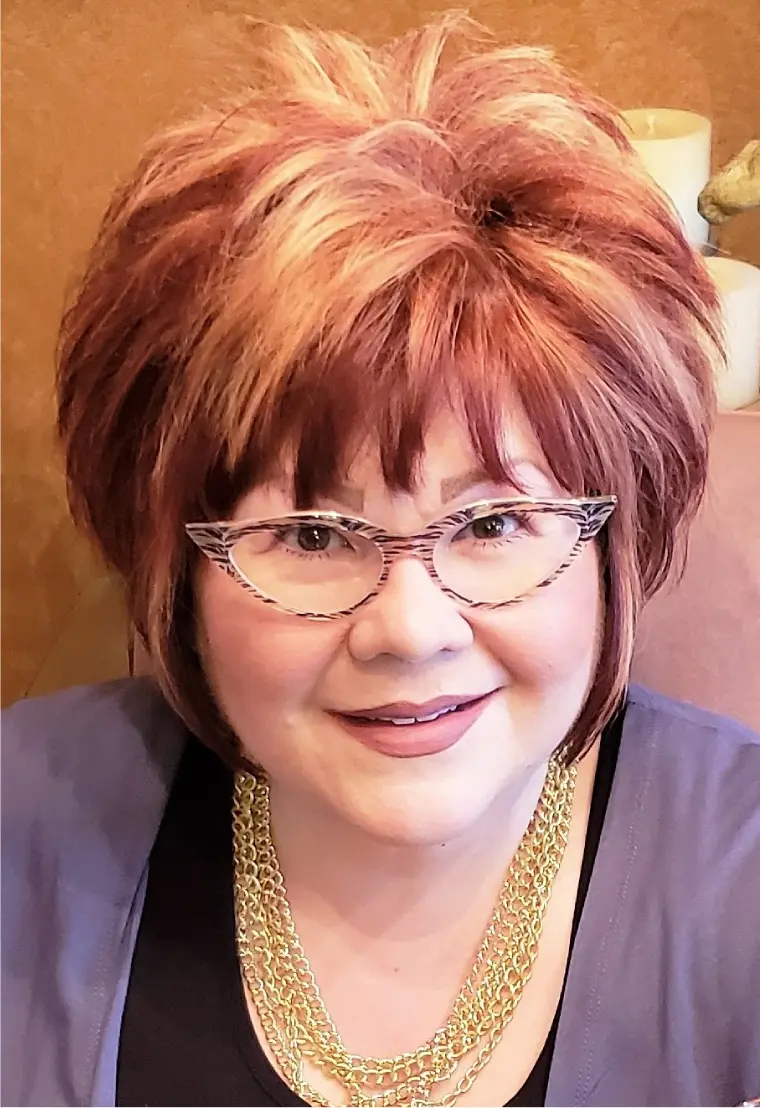 43 A woman with red hair and glasses is smiling.